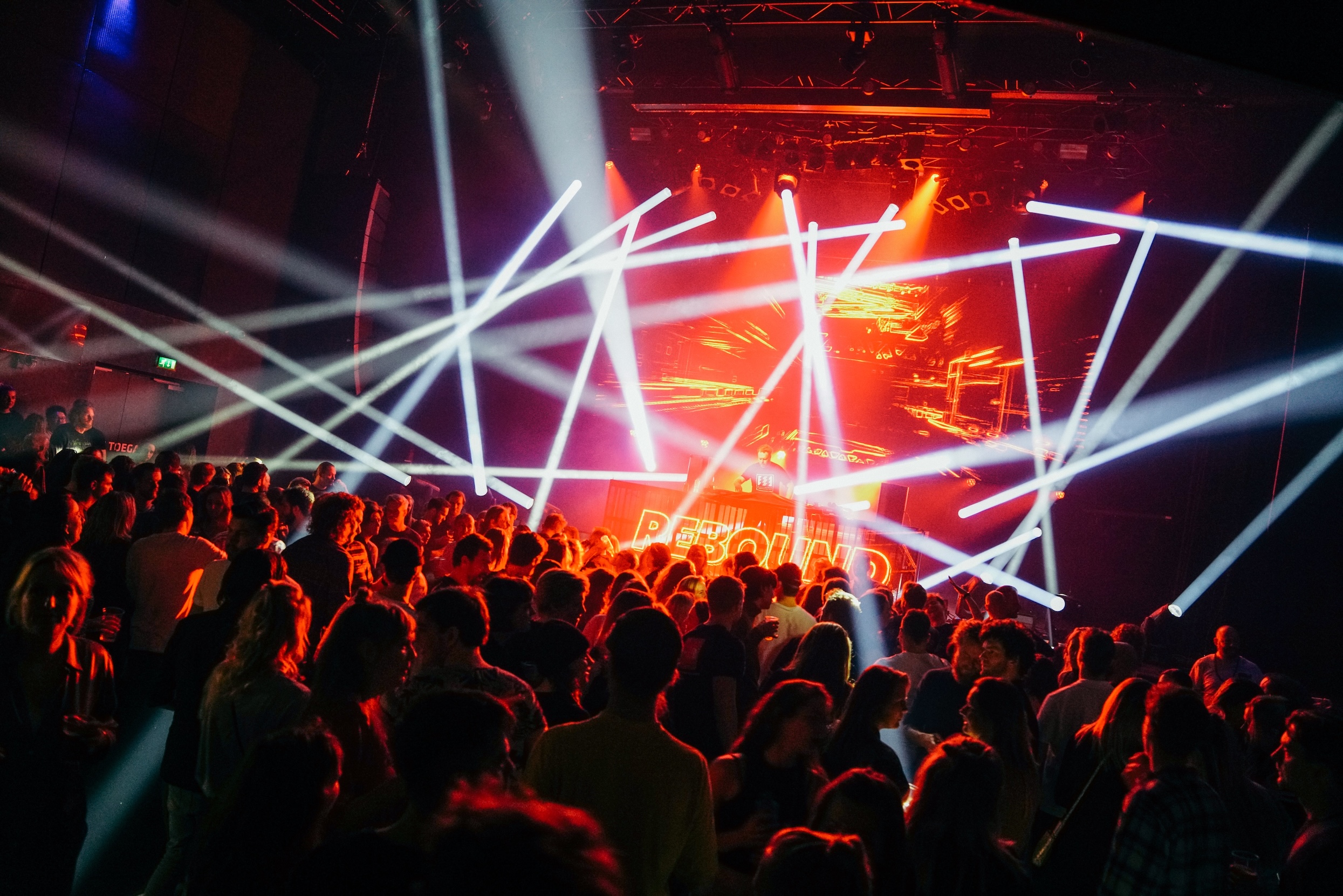 Foto van een poppodium met lichtstralen en een publiek